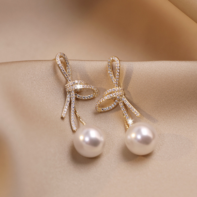 Boucles d'oreilles élégantes en or avec perles et nœud brillant